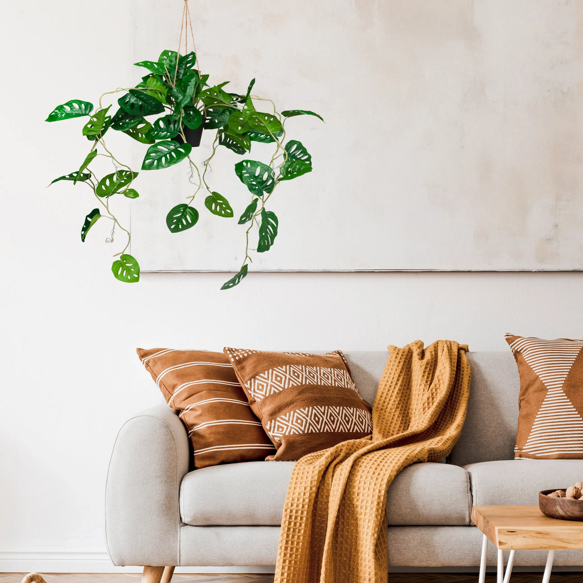 Grüne Kunstpflanze MONSTERA CLIMB als hängende Pflanze vor einer hellen Wand von hjh OFFICE