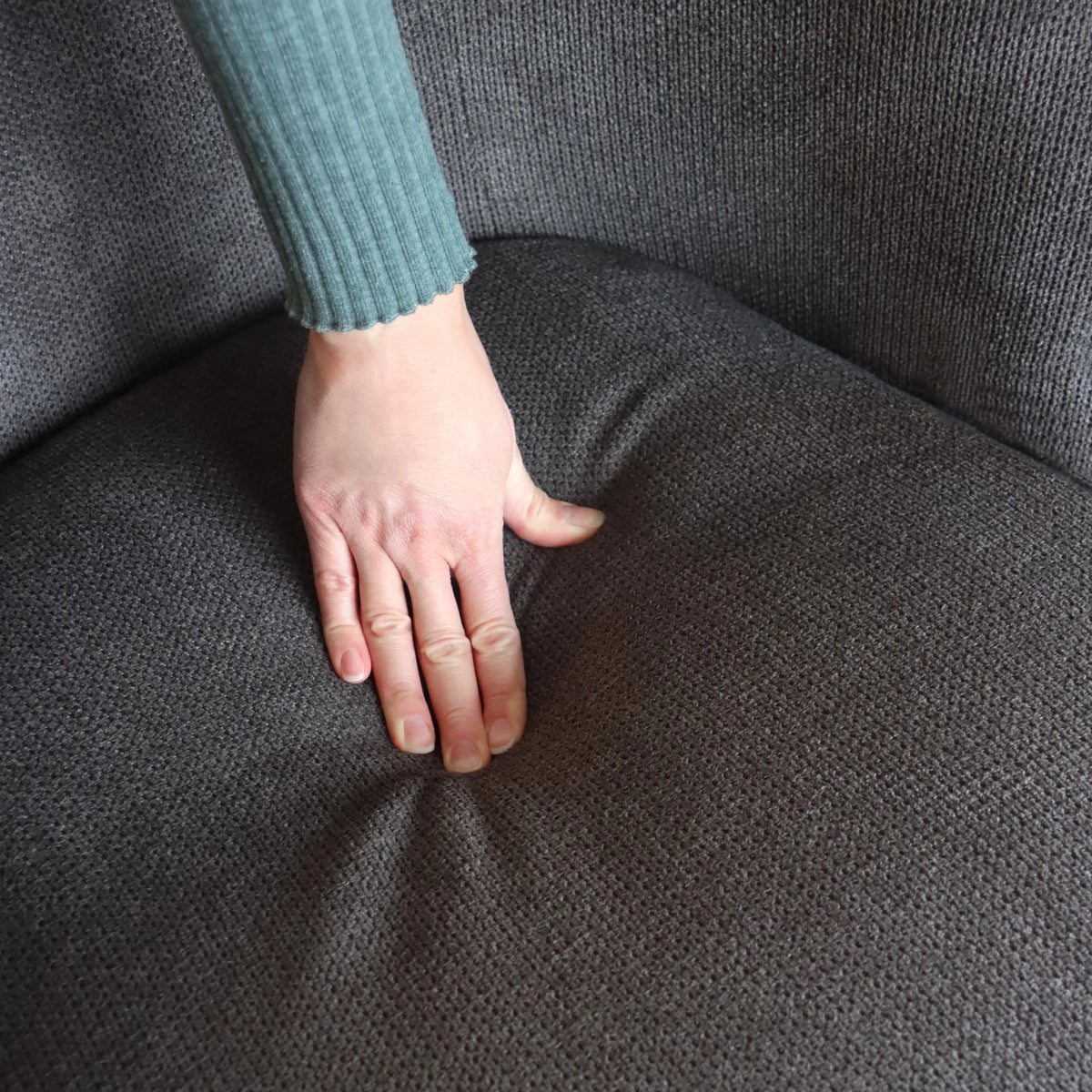 Grauer Stoffbezug der Sitzfläche des Loungesofas HAYRIVER unter einer Hand von hjh LIVING