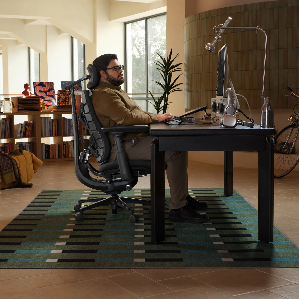 Chaise de bureau LiberNovo Maxis Manual en graphite à un bureau dans une pièce lumineuse de Libernovo