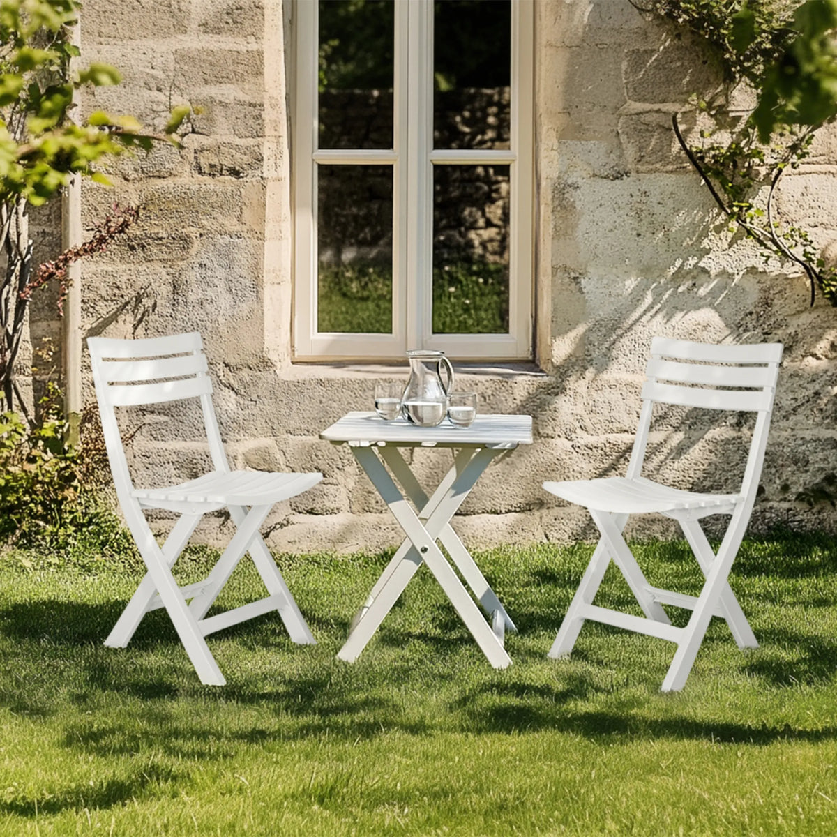 Deux chaises d'extérieur blanches TRAVANO avec table pliante assortie sur une pelouse de hjh LIVING