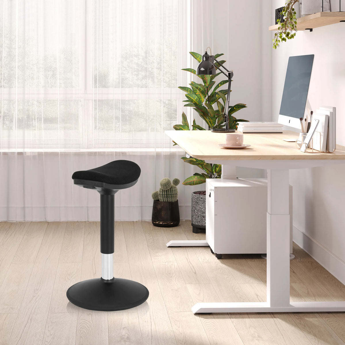 Siège assis-debout BALANCE SIT I B noir avec base ronde et assise rembourrée dans un bureau lumineux de hjh OFFICE