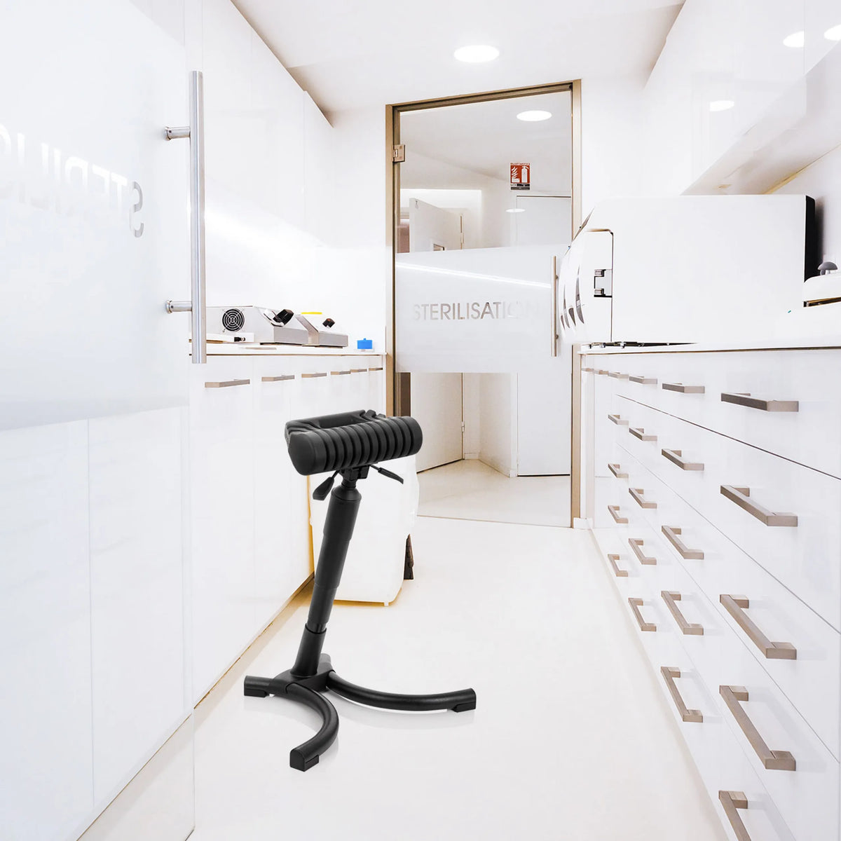 Siège assis-debout TOP WORK 33 noir avec assise rembourrée et pied en étoile dans un environnement de stérilisation clair de hjh OFFICE