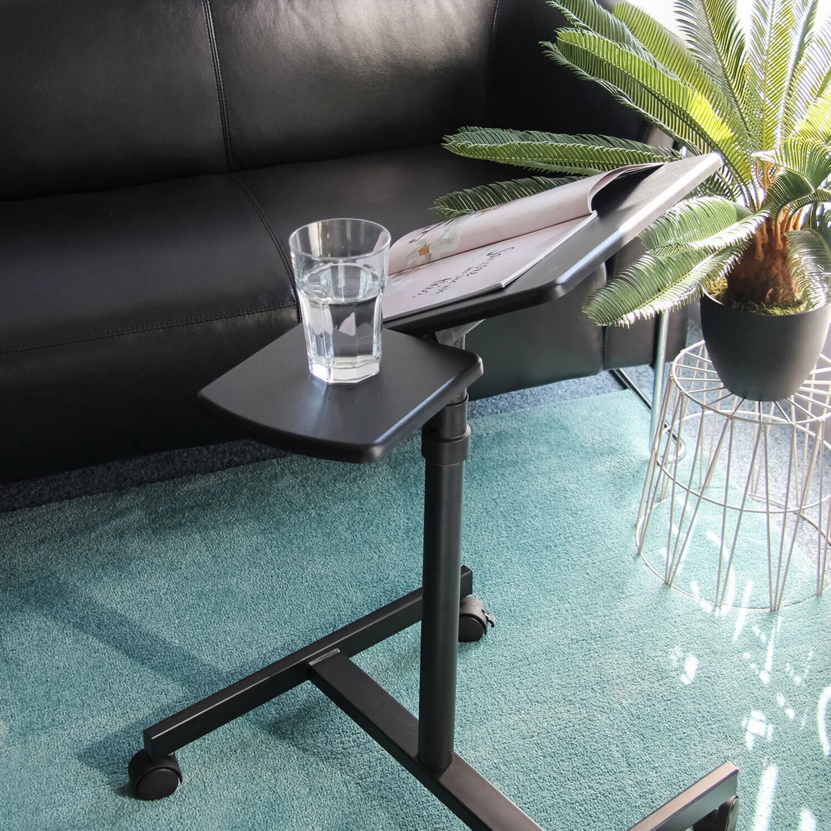 Surface noire du bureau assis-debout VM-SL avec un verre et un magazine sur un tapis de hjh OFFICE