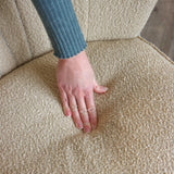 Tissu texturé beige du fauteuil de salon MANISO avec une main posée sur l'assise de hjh LIVING