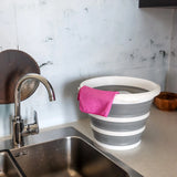 Conteneur pliable CLEAN SILR gris et blanc avec un chiffon rose sur un plan de travail à côté d'un évier de hjh OFFICE