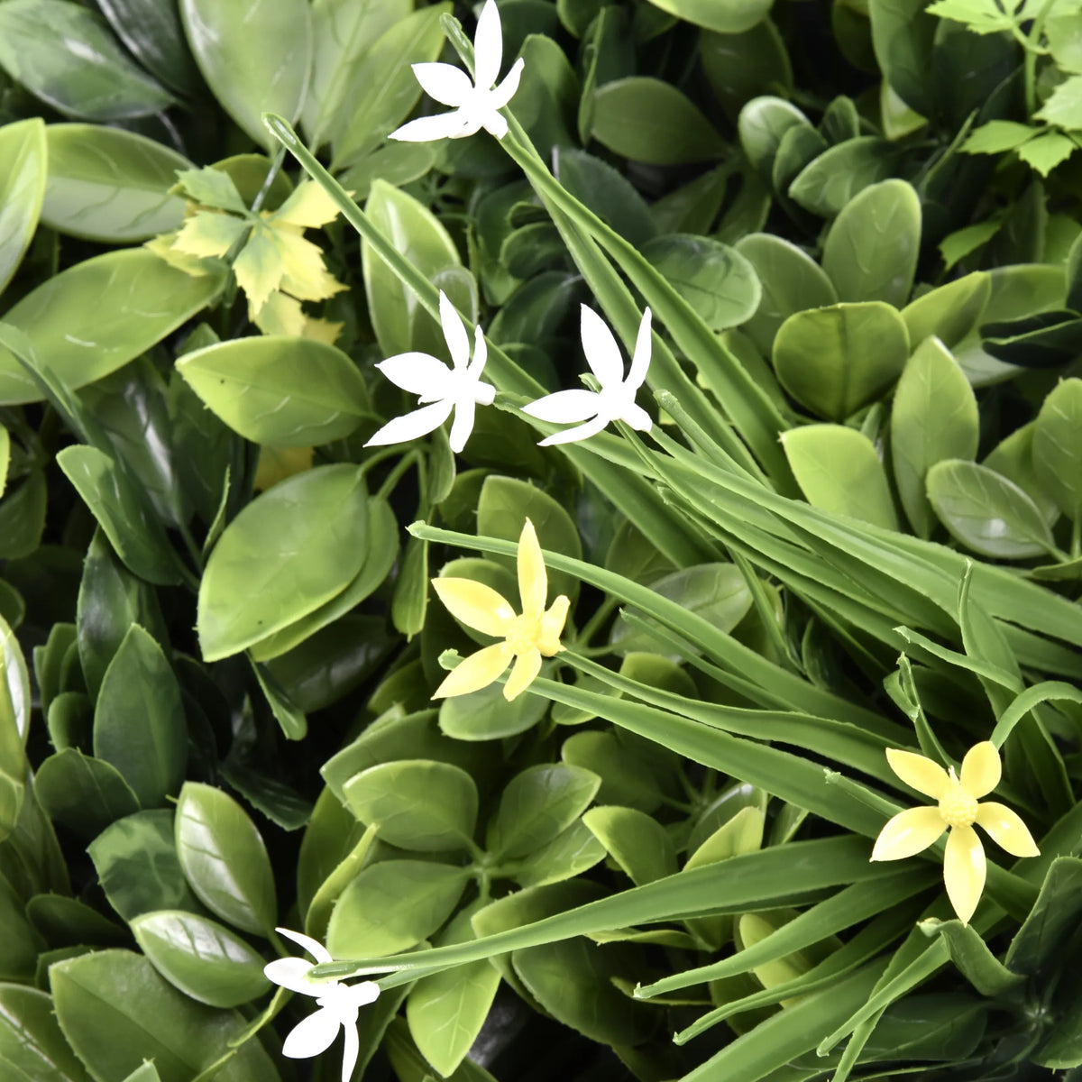 Grüne Blätter mit kleinen weißen und gelben Blüten der Pflanzenmatte LEAFLUXE WALL 2 von hjh LIVING