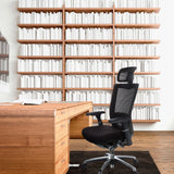 Siège de bureau haut de gamme NOVA PRO I noir avec appuie-tête et dossier en maille devant un bureau en bois de hjh OFFICE