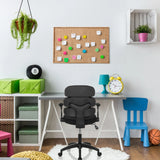 Chaise pivotante pour des enfants KID ERGOLINO B noire avec accoudoirs et roulettes devant un bureau de hjh OFFICE