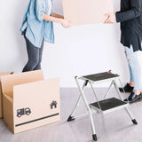 Échelle pliante blanche SOLID W1 avec deux marches noires à côté d'un carton de déménagement de hjh OFFICE