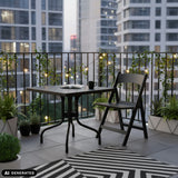 Table pliante TRAVANO T1 noire de 79 × 79 cm sur un balcon de hjh LIVING (image générée par IA)