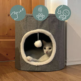 Grotte pour chat PAWY R grise avec bordure en fourrure blanche, balle de jeu intégrée et un chat à l'intérieur de hjh LIVING