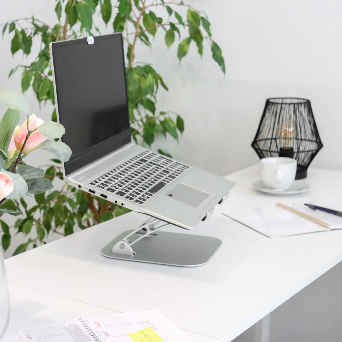 Silberne Laptopunterlage LAPTOP STAND mit verstellbarem Gestell auf einem weißen Schreibtisch von hjh OFFICE