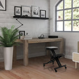 Tabouret à genoux ORTHONI noir avec roulettes devant un bureau en bois dans une pièce lumineuse de hjh OFFICE