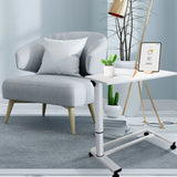 Bureau assis-debout blanc STAND II sur roulettes à côté d'un fauteuil gris de hjh OFFICE